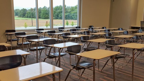 aula sin estudiantes, solo escritorios vacíos.