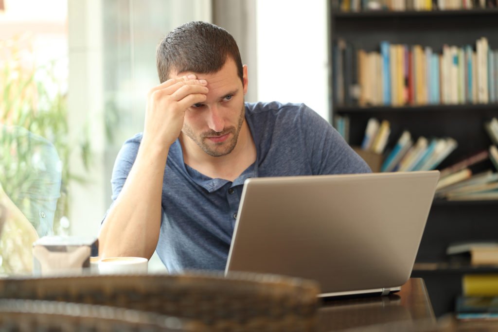 Registered sex offender behind a computer looking distressed at seeing his information online