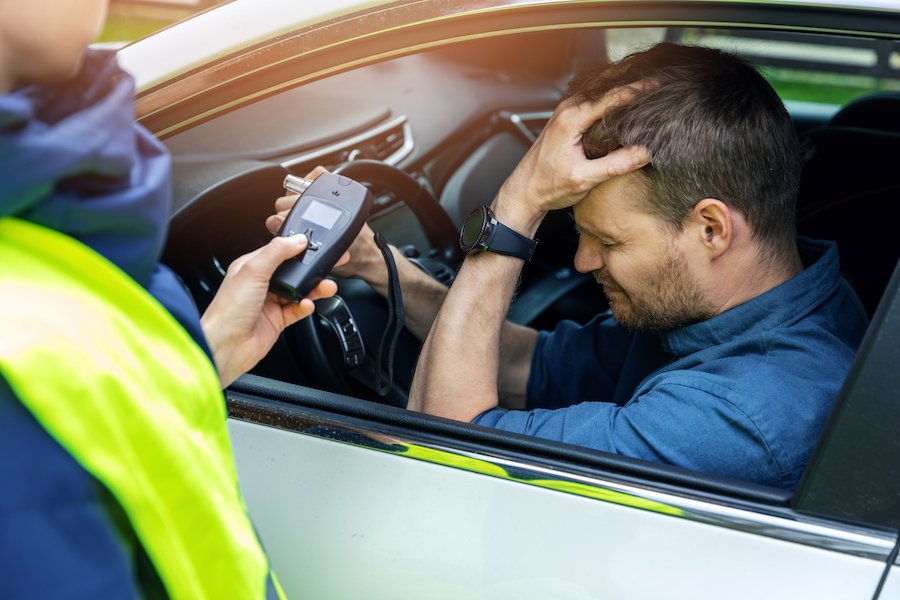 Policía administrando un alcoholemia a un sospechoso de DUI en el coche