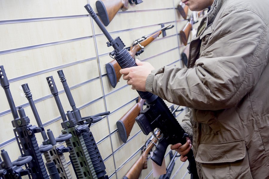 Hombre en tienda de armas sosteniendo rifle