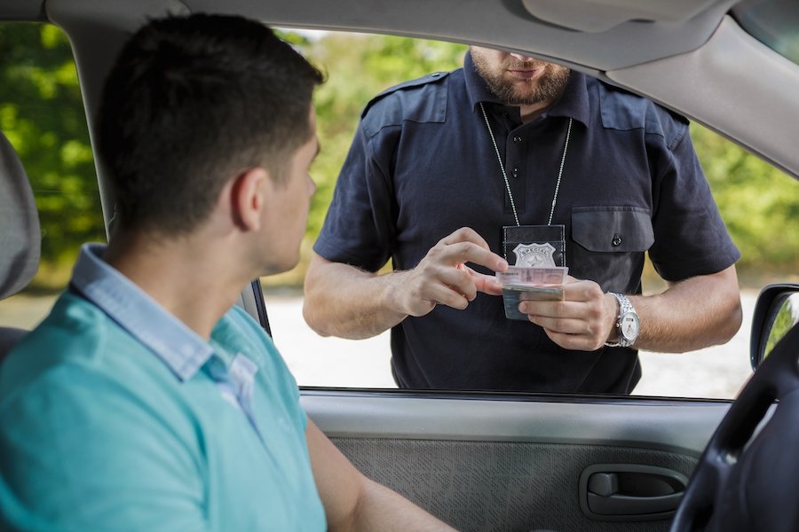 Oficial de policía inspeccionando la licencia de conducir después de una parada de tráfico