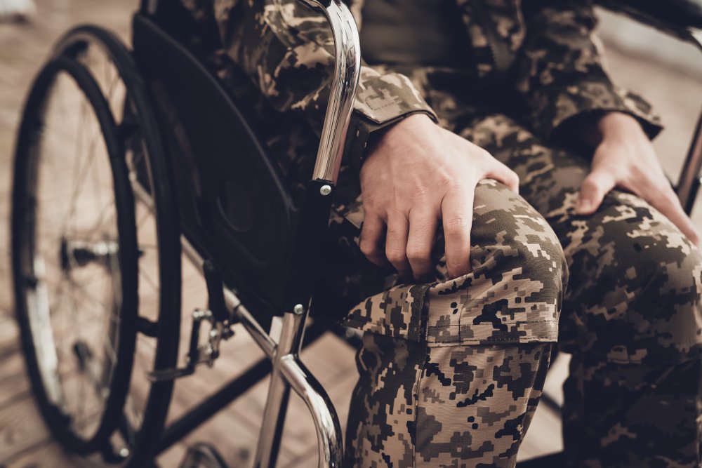 Un hombre vestido con uniforme militar está sentado en una silla de ruedas herido.