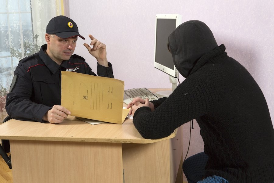 Un libertad condicional con una sudadera con capucha registrándose con un oficial de libertad condicional en su escritorio