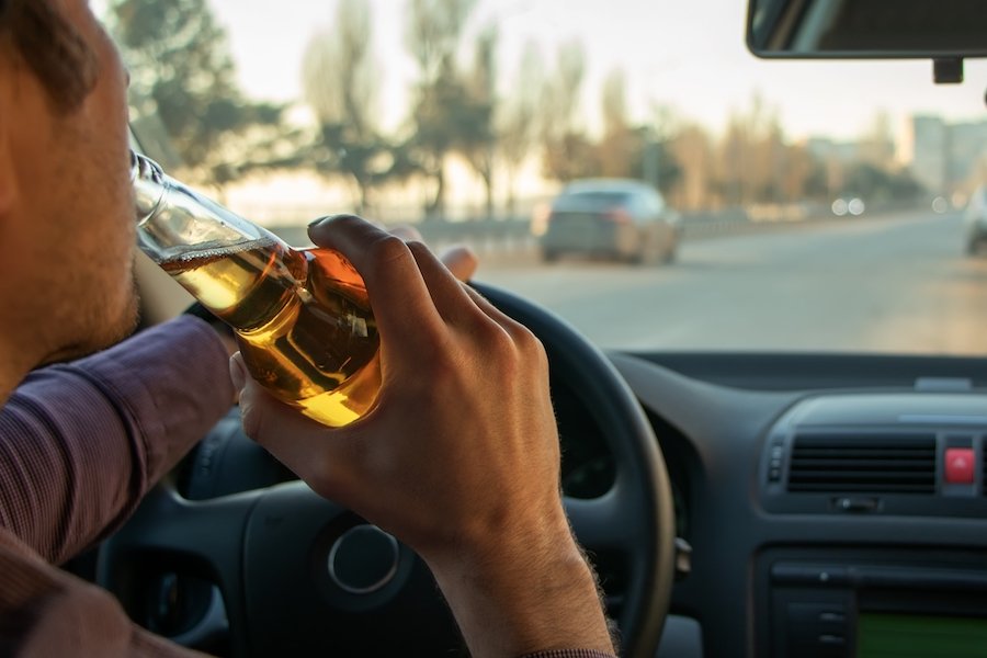 Hombre bebiendo cerveza mientras conduce