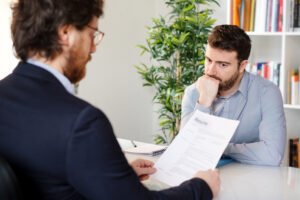 Job applicant looking on nervously as the interviewer reviews his background check, which includes a felony conviction