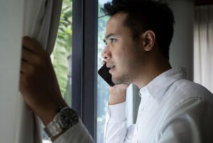 Man on the phone calling the police to report a crime he sees happening outside of his window