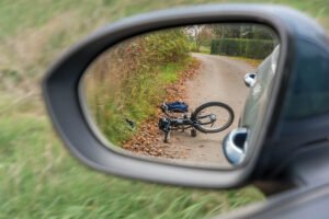 Car's side mirror showing the reflection a damaged bicycle lying on the road that the car just hit