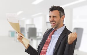 Jubilant man in a business suit pumping his fist in victory and holding a legal document after learning that the court has granted his petition for factual innocence